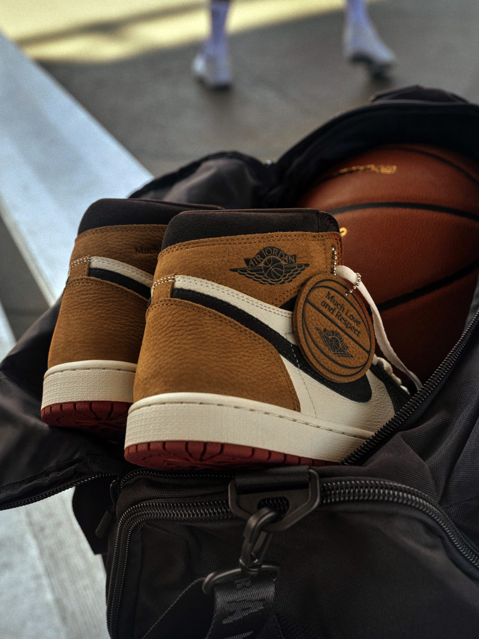 Basketball-shaped leather hangtag on the Air Jordan 1 High OG Love Letter reading Much Love and Respect, next to a basketball