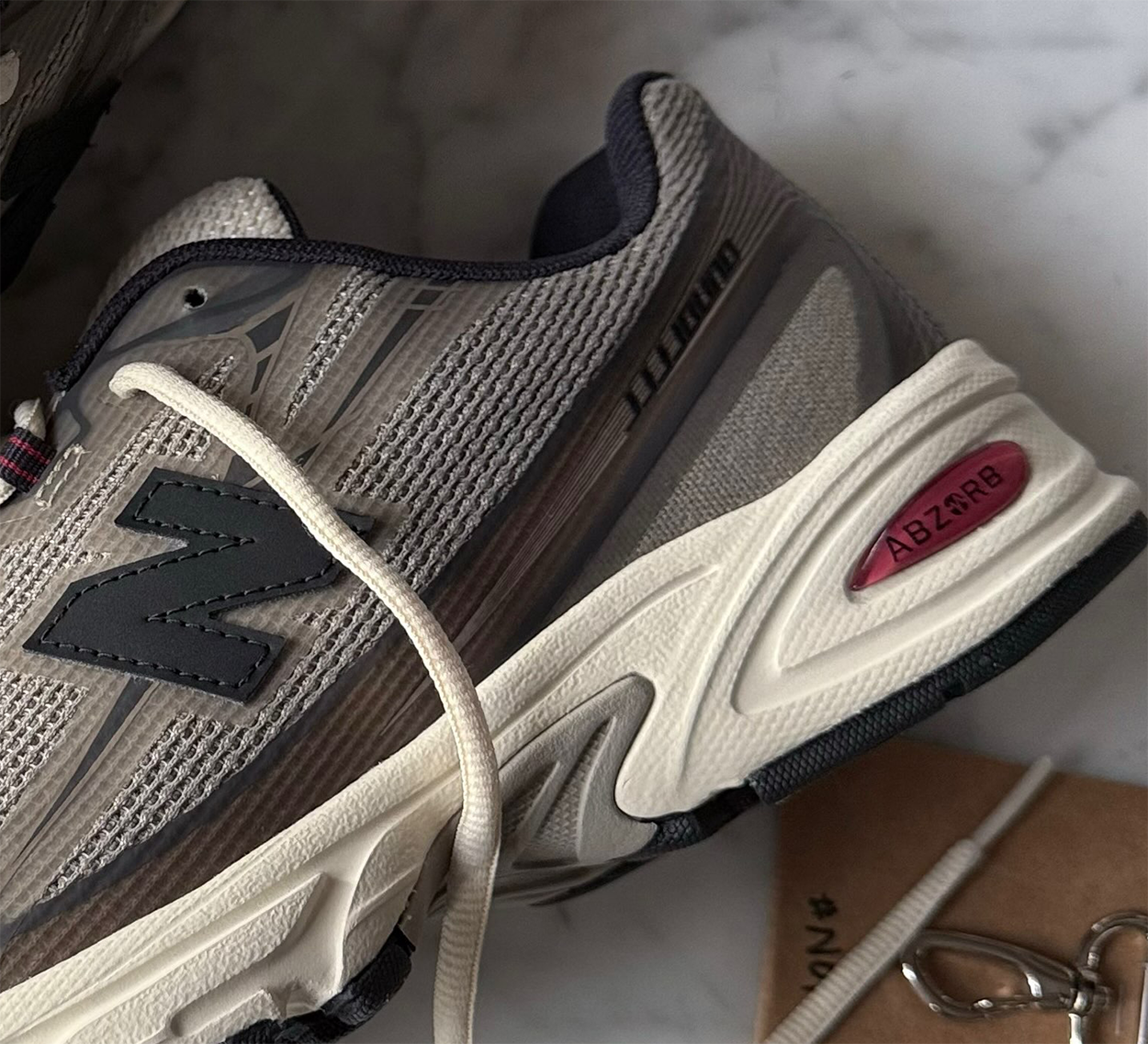 Close-up of the JJJJound x New Balance 740N Mushroom heel showing the cream midsole, red ABZORB unit and black lateral N logo