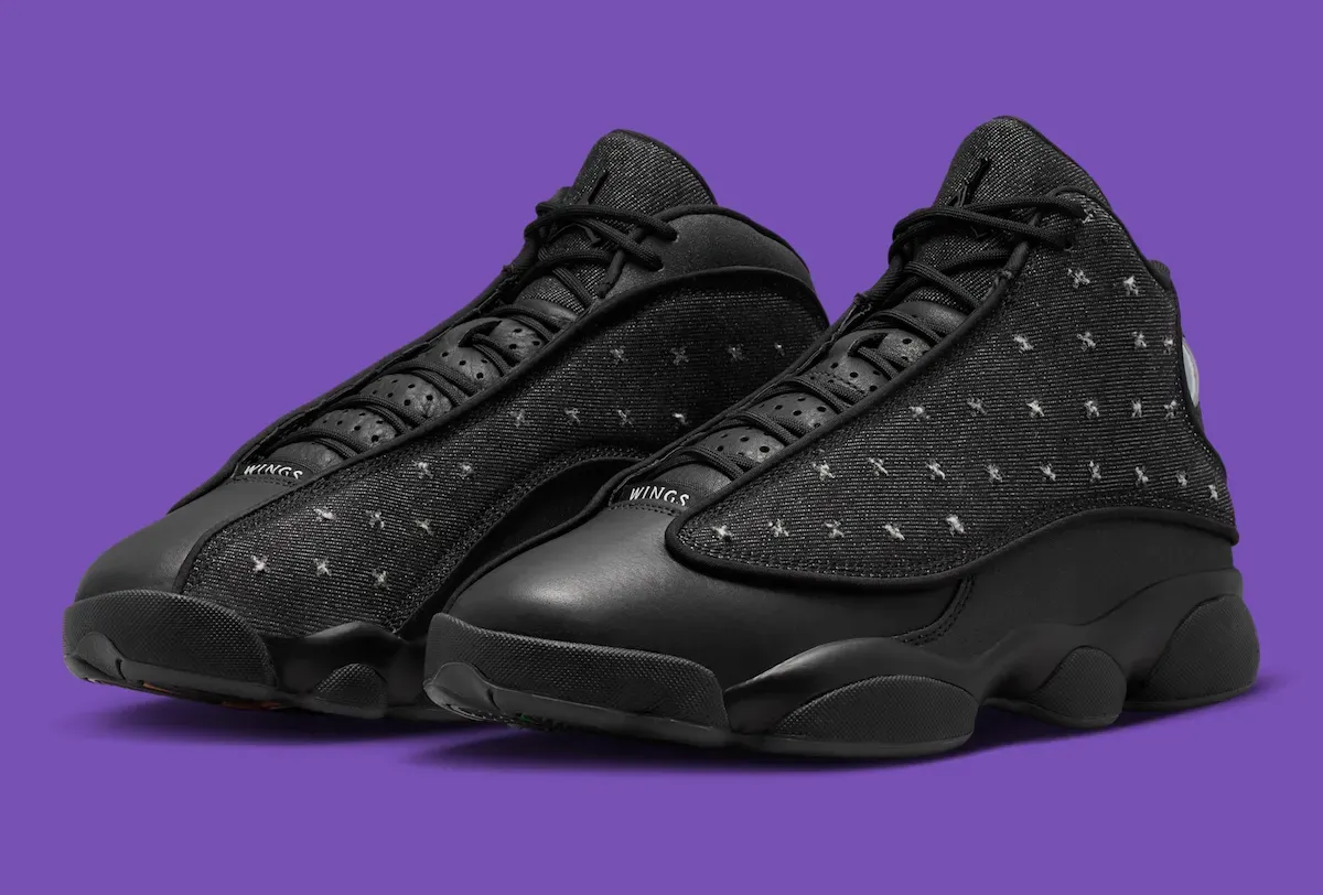 Air Jordan 13 Wings IX1872-001 three-quarter pair view showing black denim upper with white X-stitching and WINGS branding at the toe