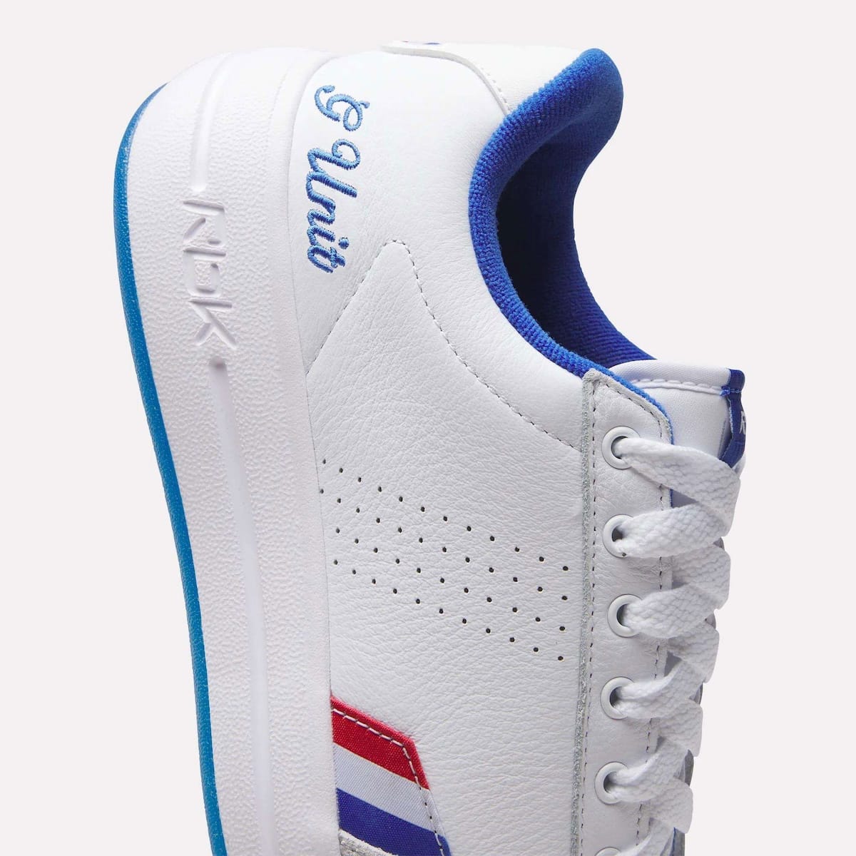 Close-up of the Reebok G-Unit G6 heel showing royal blue G Unit embroidery, perforated venting and the red white and blue stripe badge