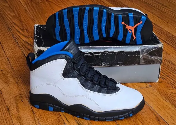 The original 1995 Air Jordan 10 "Knicks" in white leather with a blue outsole and orange Jumpman, resting on its box