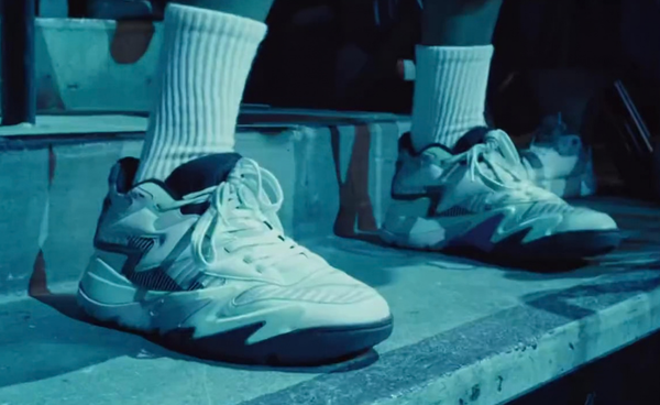 J. Cole's Dreamer Indie 5000 sneakers in white leather with blue zig-zag panels, worn on concrete steps